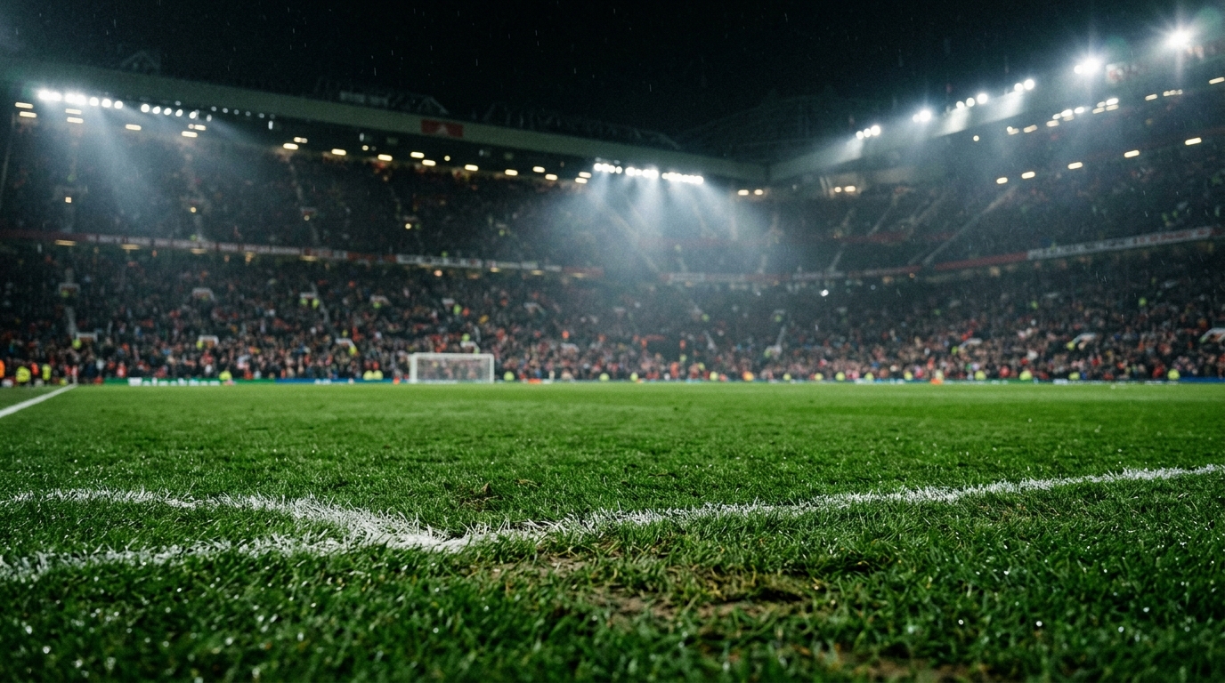 Green football pitch under floodlights with a blurred crowd in the background