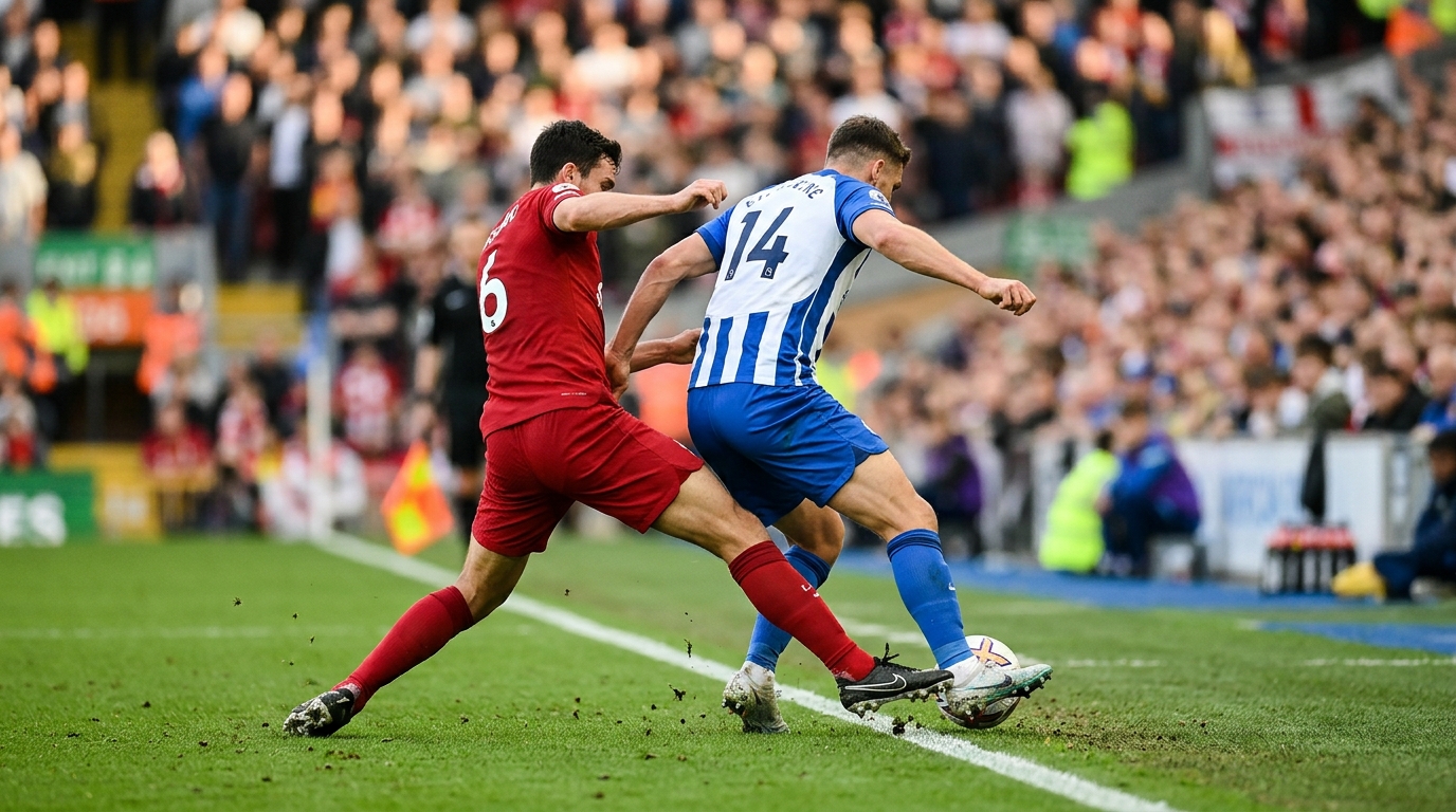 Two football players in red and blue-white striped kits contesting the ball near the touchline at Anfield.